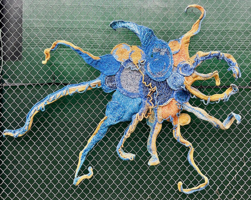 large fiber artwork attached to chain link fence