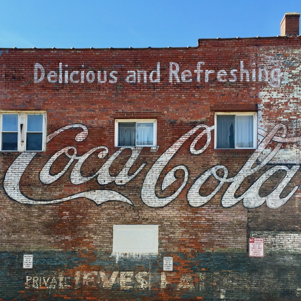 brick wall painted with faded advertisement for Coca-Cola