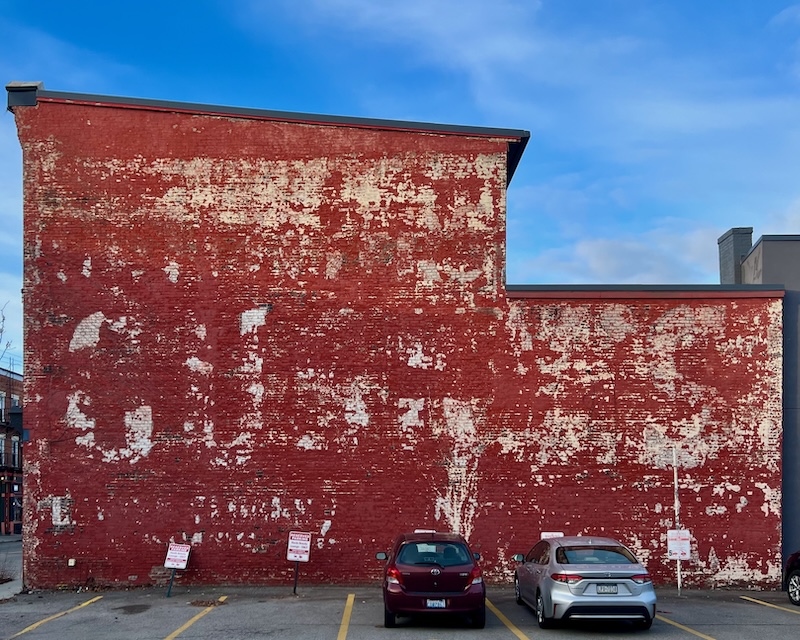 faded hand-painted sign for clothing store painted on brick wall