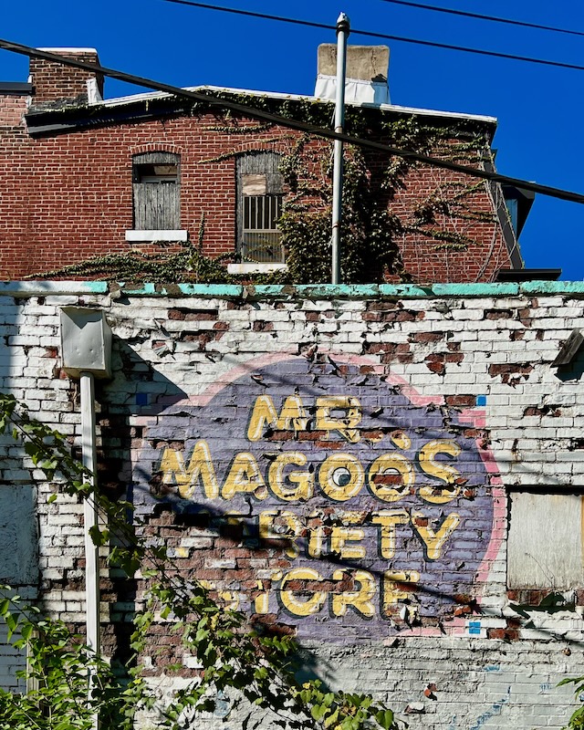 faded hand-painted sign for variety store painted on brick wall