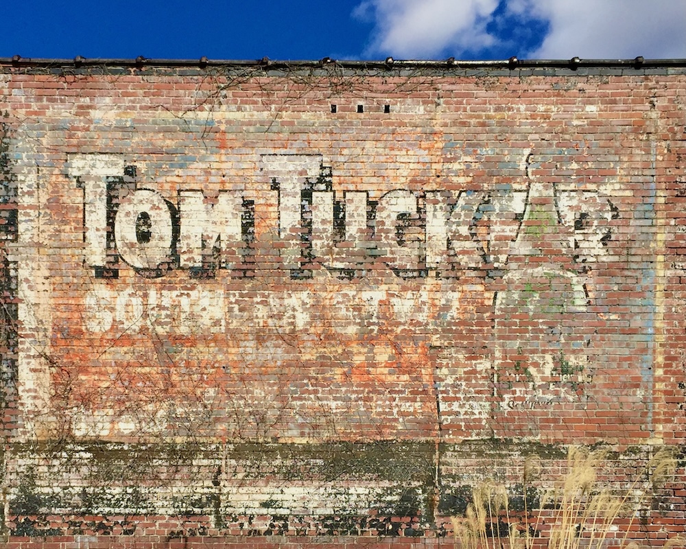 brick wall painted with faded advertisement for Tom Tucker ginger ale