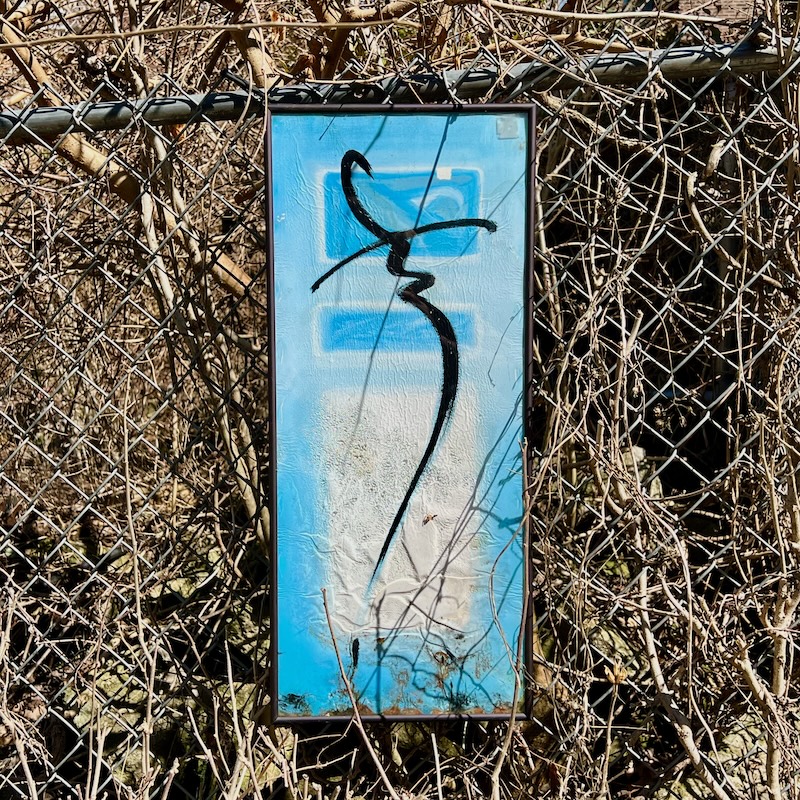 abstract painting hung on chain link fence