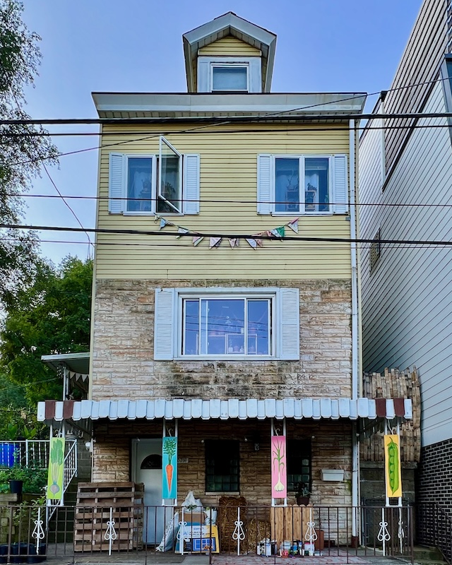 home with paintings of vegetables on front porch