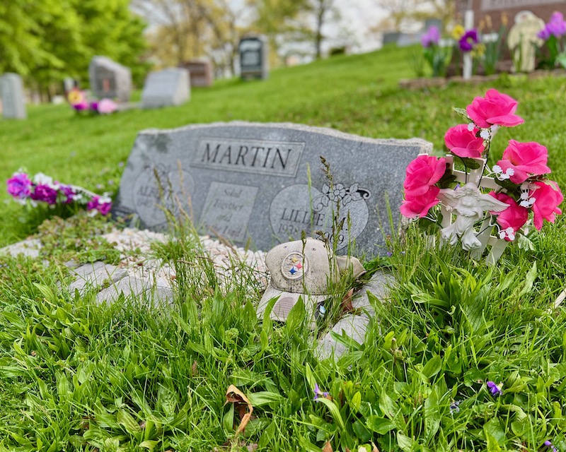 grave marker decorated with Pittsburgh Steelers ball cap