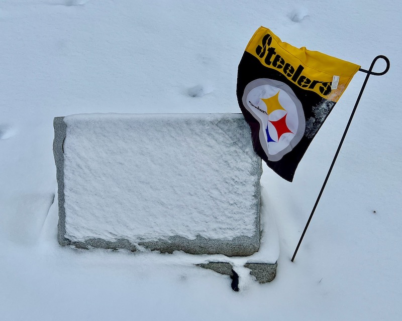grave marker covered in snow decorated with Pittsburgh Steelers flag