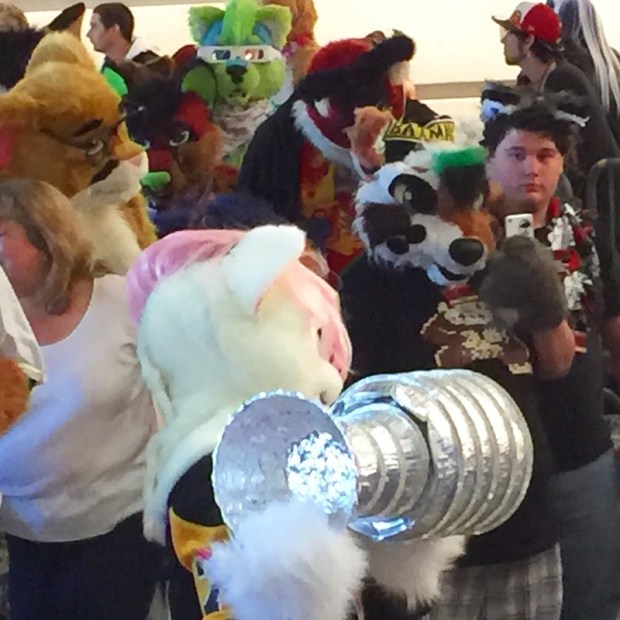 Person in fursuit carrying a homemade model of the Stanley Cup