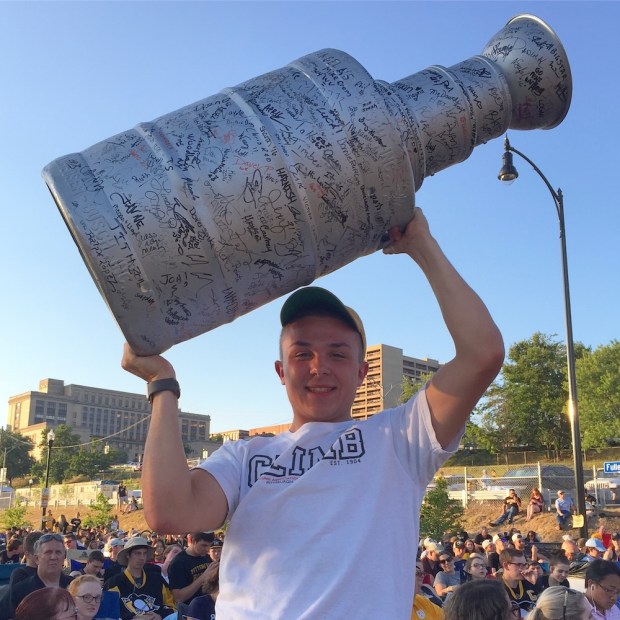 Boy with homemade model of the Stanley Cup among Pittsburgh Penguins hockey fans