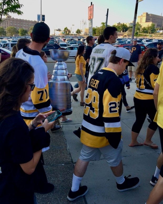 Man with homemade model of the Stanley Cup among Pittsburgh Penguins hockey fans