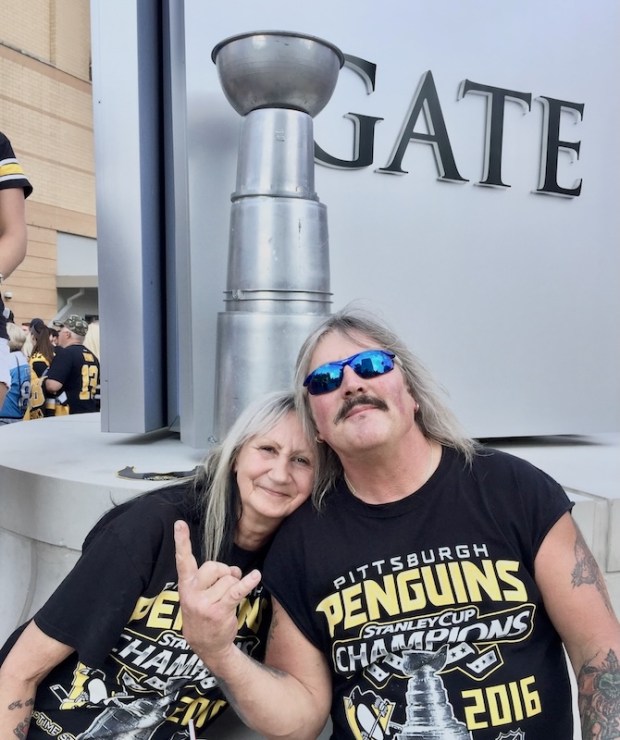 Couple posing in front of homemade model of the Stanley Cup in front of PPG Paints Arena